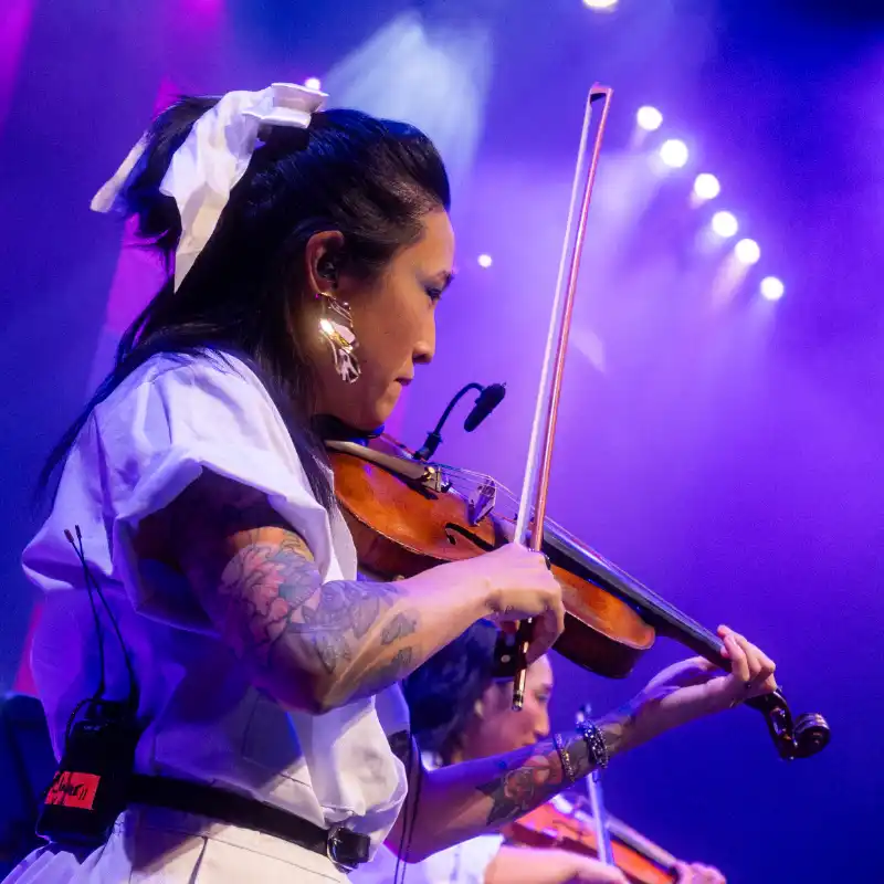 A violinist dressed in striking white plays with the New Wave Orchestra at Balboa Theatre in San Diego